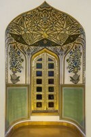 Um quarto com um arco decorativo, uma porta grande e elaborada, e dois painéis laterais com motivos florais.