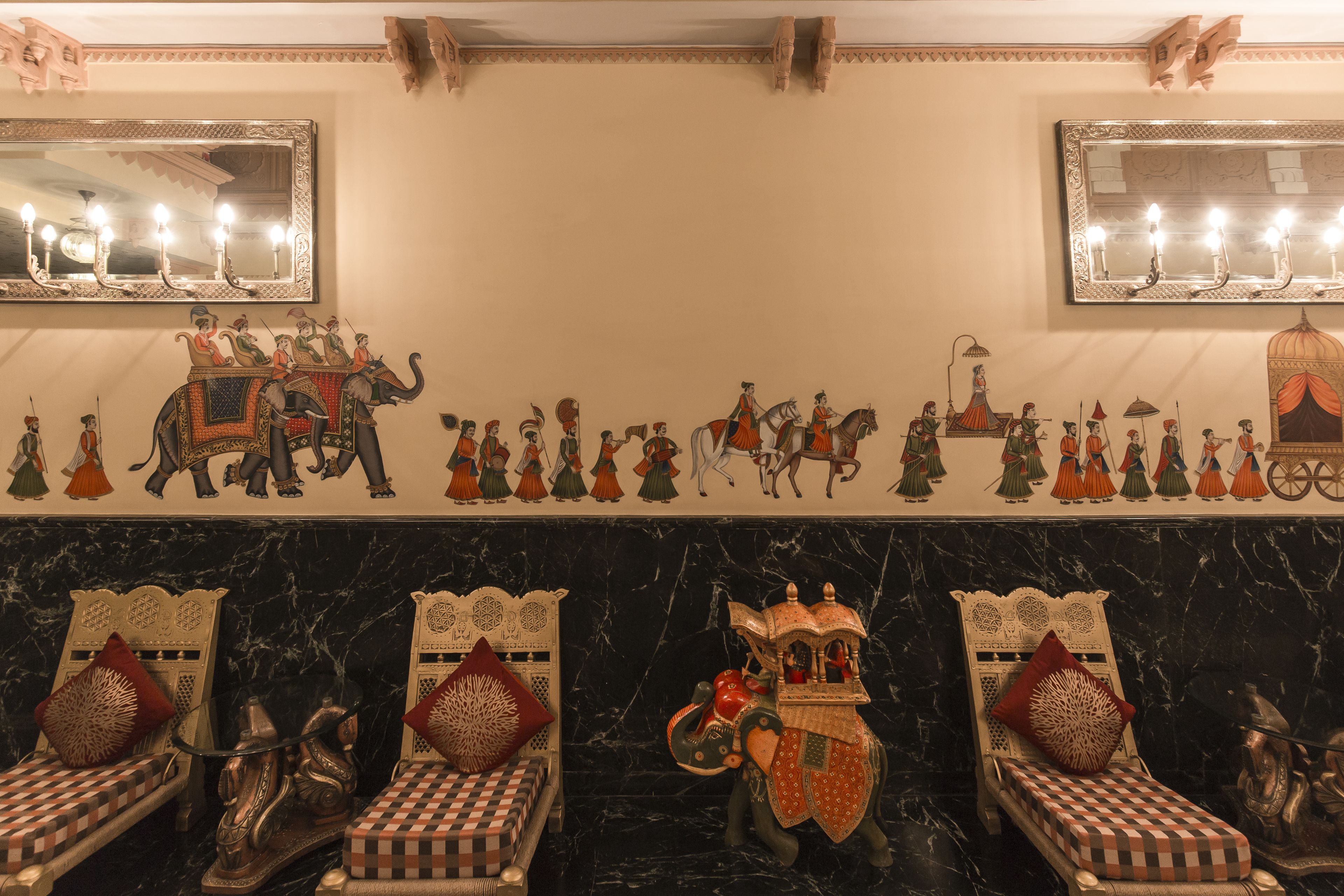 Quarto com piso de mármore preto, cadeiras ornamentadas com estofamento xadrez e parede decorada com um mural de uma procissão.