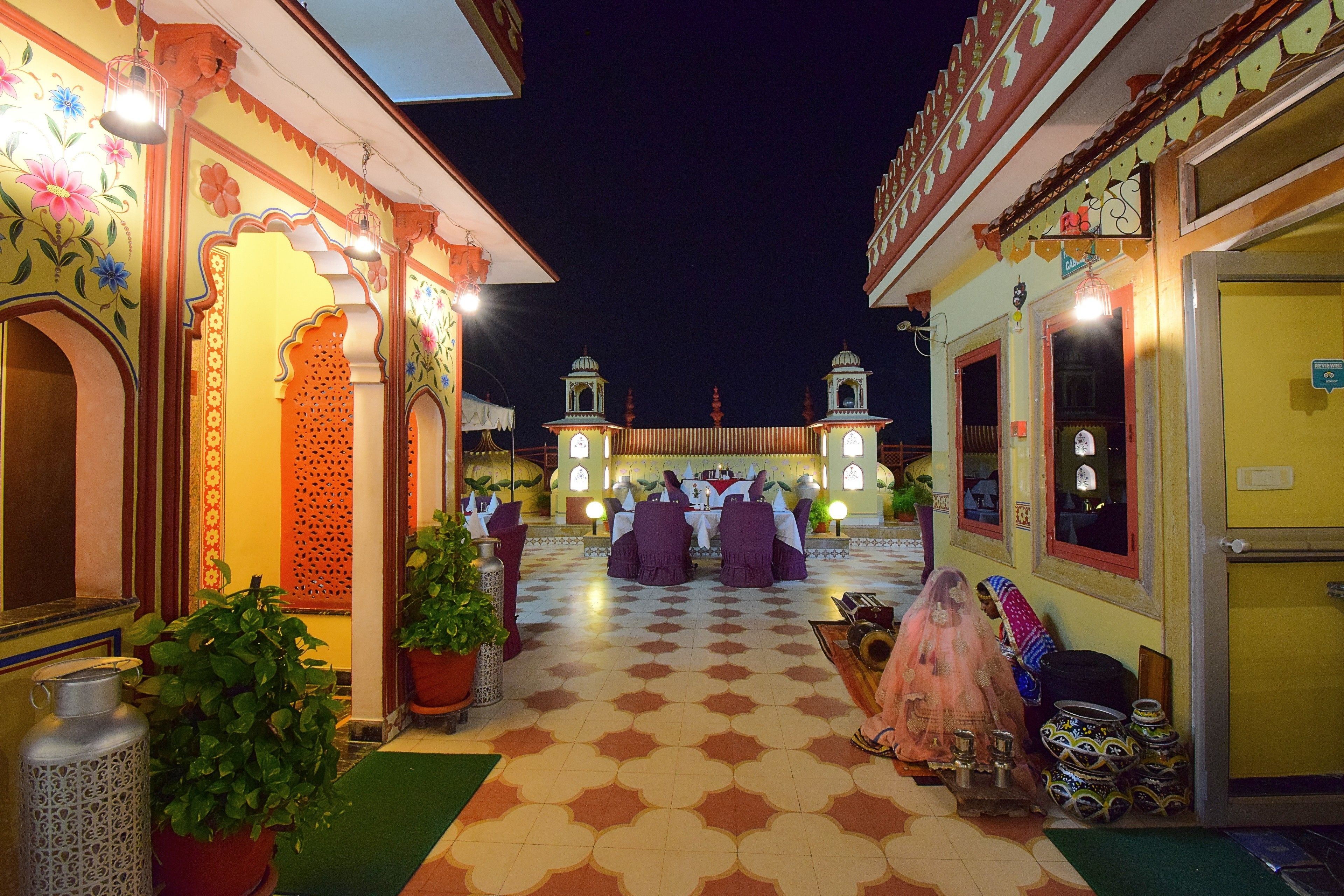 A courtyard with a checkered floor, traditional architecture, and a dining area with tables and chairs.