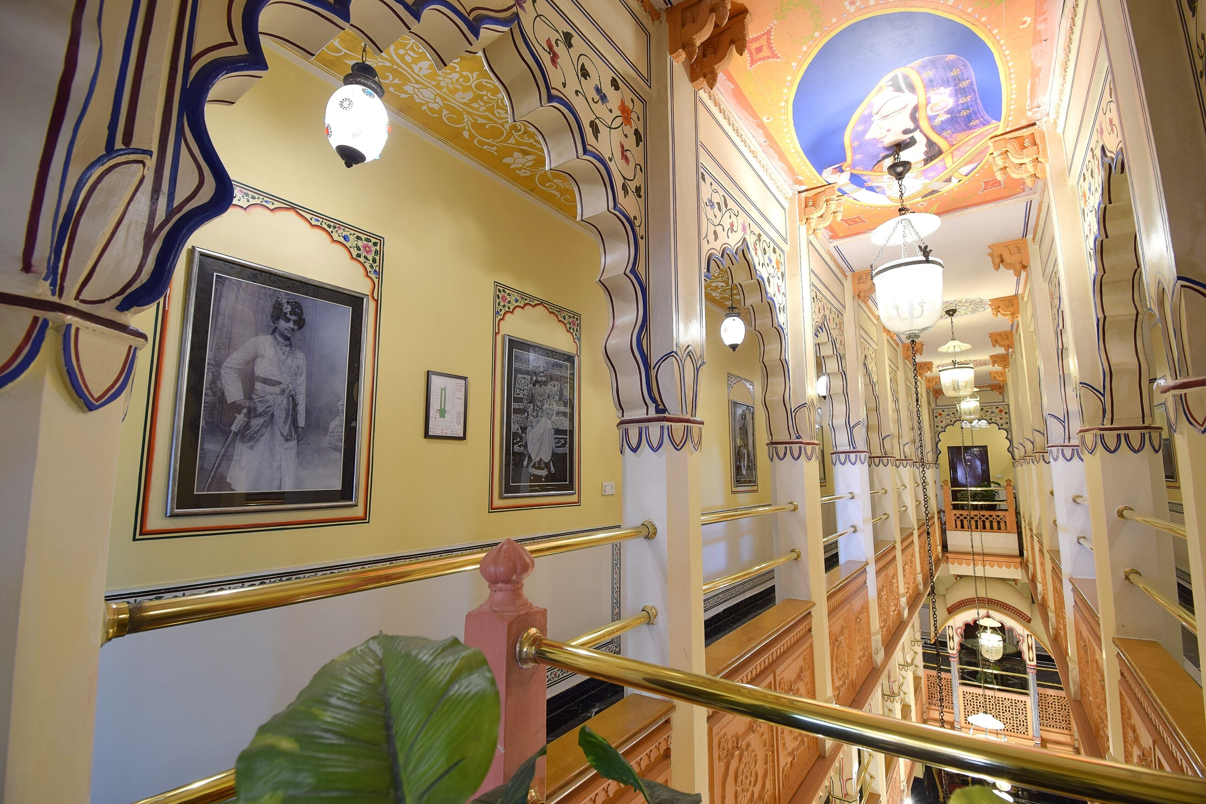 A grand staircase with ornate railings and framed pictures on the walls.