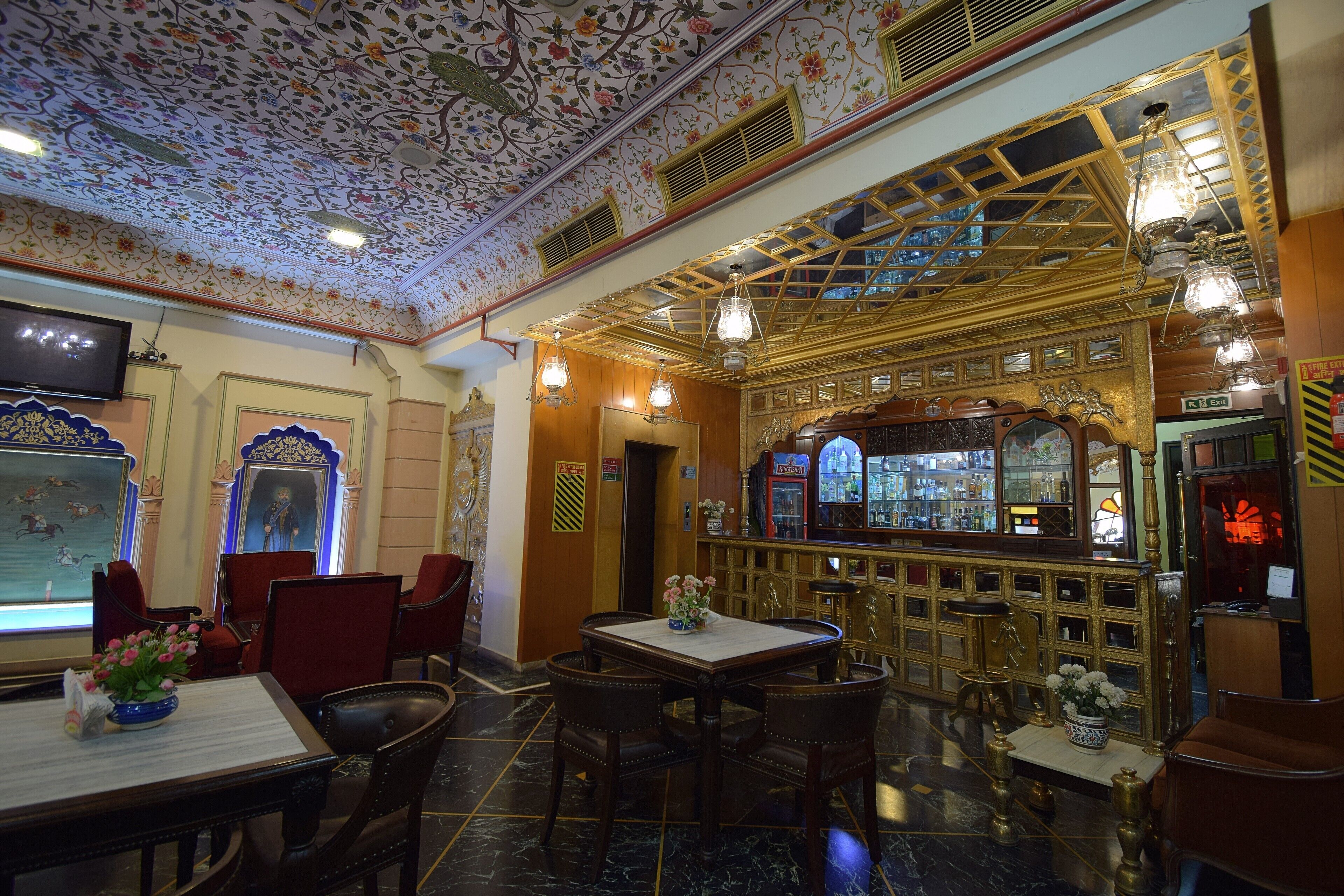 A bar area with a counter, seating, and a decorative ceiling.