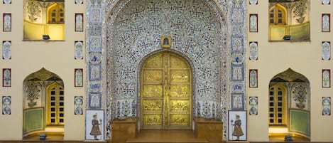 Una entrada imponente con una puerta grande y ornamentada, intrincados detalles de azulejos y pequeñas estatuas.