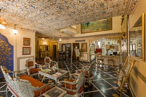 A luxurious lobby with ornate furniture, a check-in desk, and a large mirror. - Umaid Mahal - A Heritage Style Boutique Hotel (Jaipur)