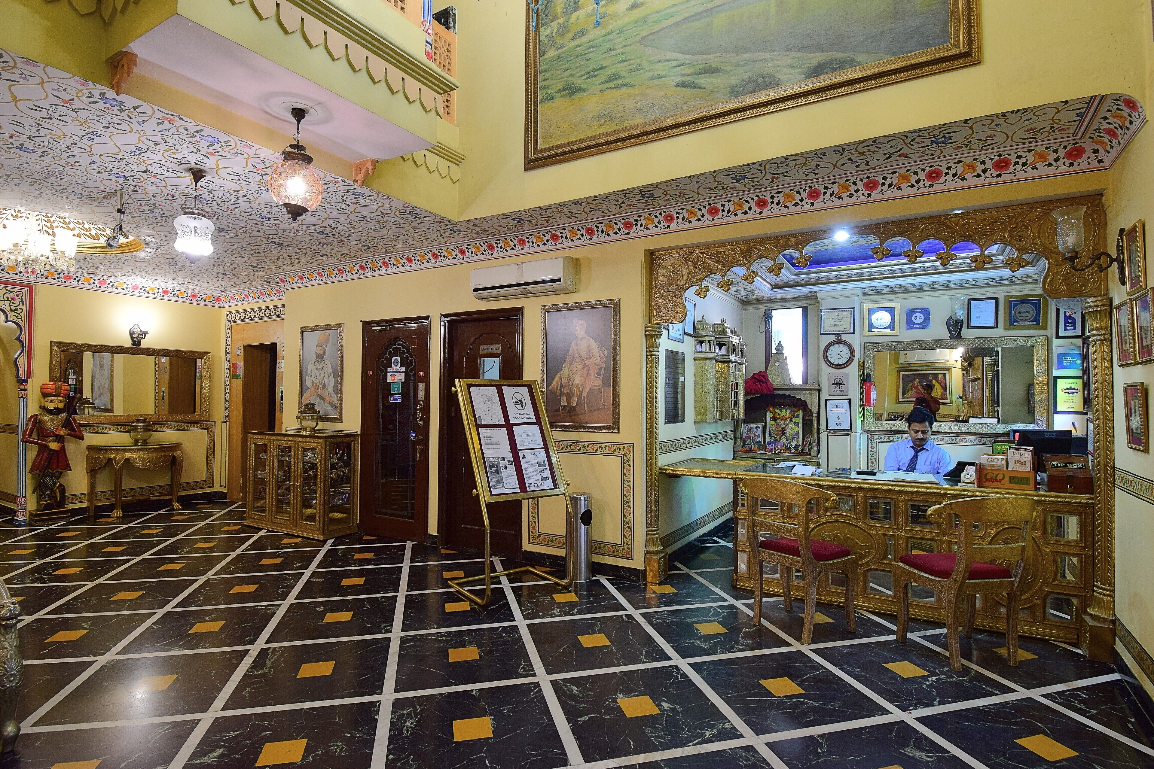 A lobby with a check-in counter, a reception desk, and a large mirror.