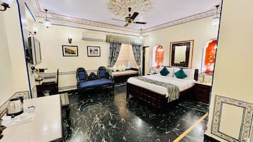 A hotel room with a bed, a desk, a chair, a ceiling fan, and a decorative ceiling.
