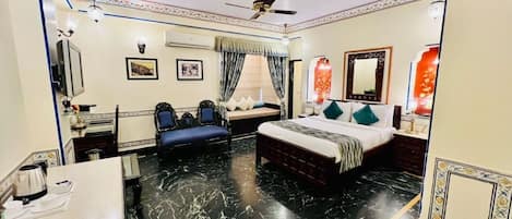 A hotel room with a bed, a desk, a chair, a ceiling fan, and a decorative ceiling.