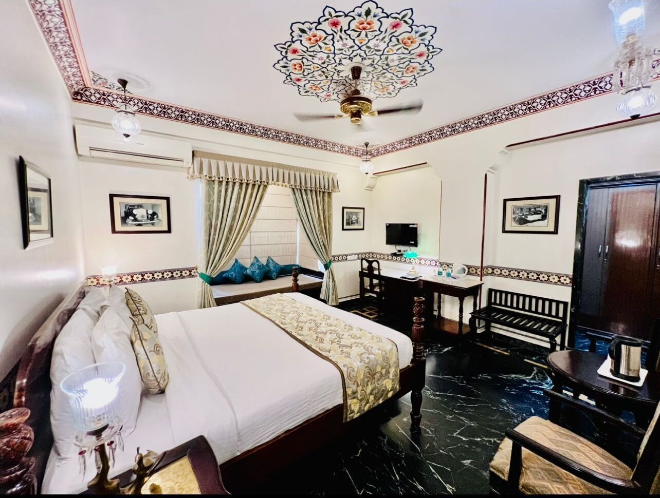 Una habitación de hotel con cama, escritorio, silla, televisor y armario.