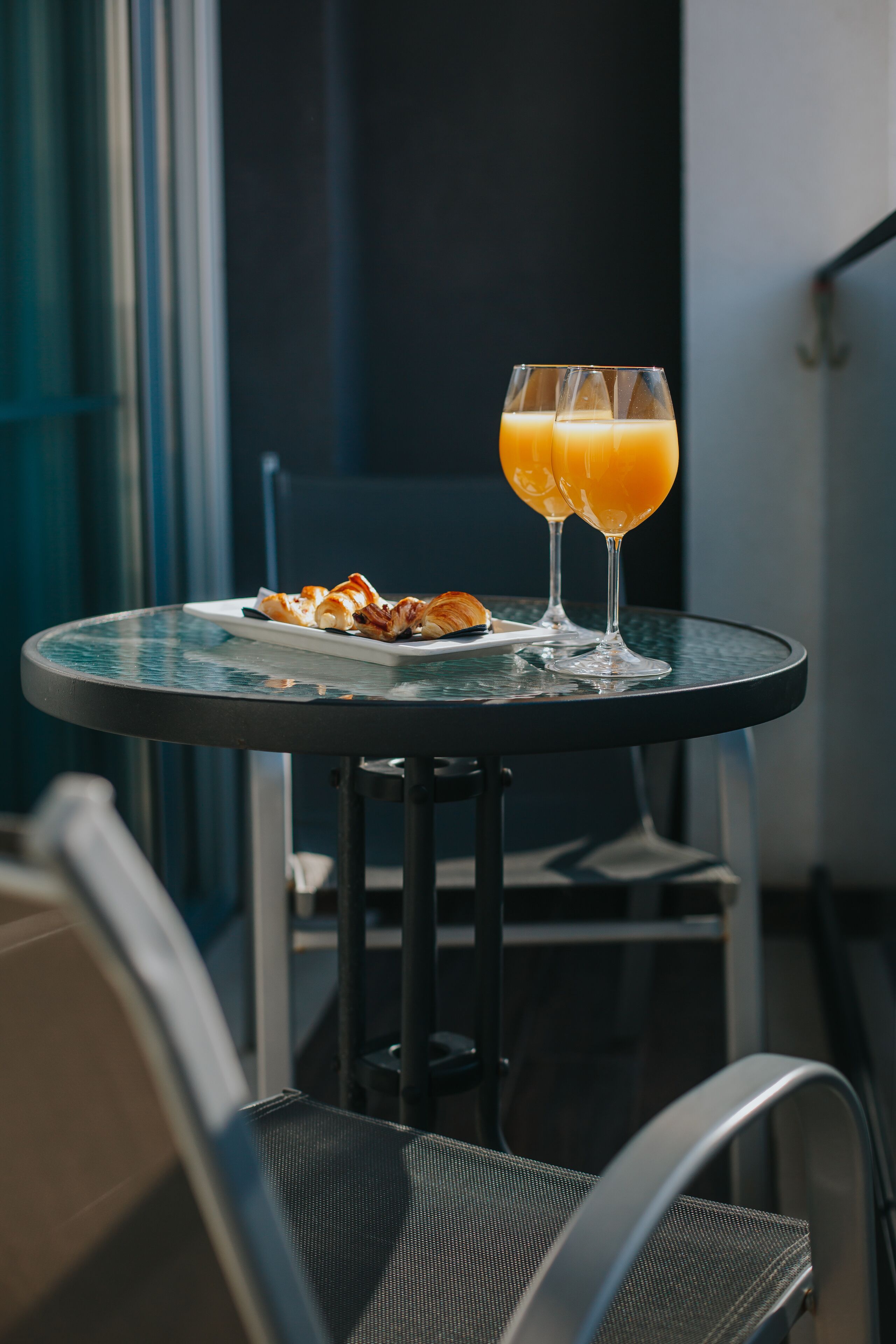 Une table ronde avec une assiette de croissants et deux verres de jus d’orange.