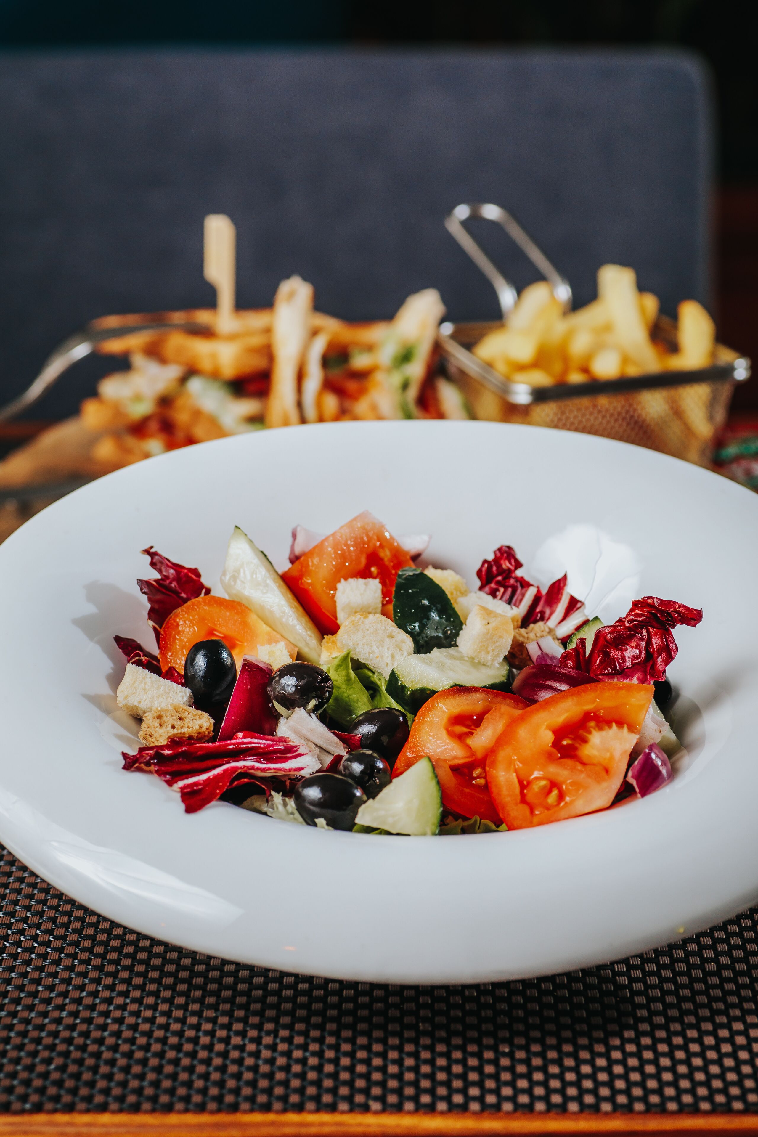 Ensalada de hojas verdes mixtas con croutons y una porción de papas fritas.