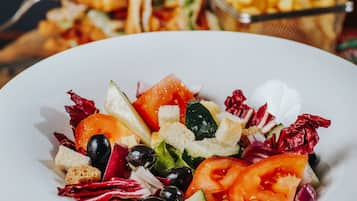 Ensalada de hojas verdes mixtas con croutons y una porción de papas fritas.