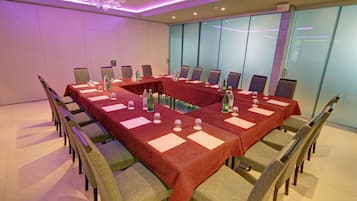 Un salón de conferencias con una larga mesa, sillas y separadores de vidrio.