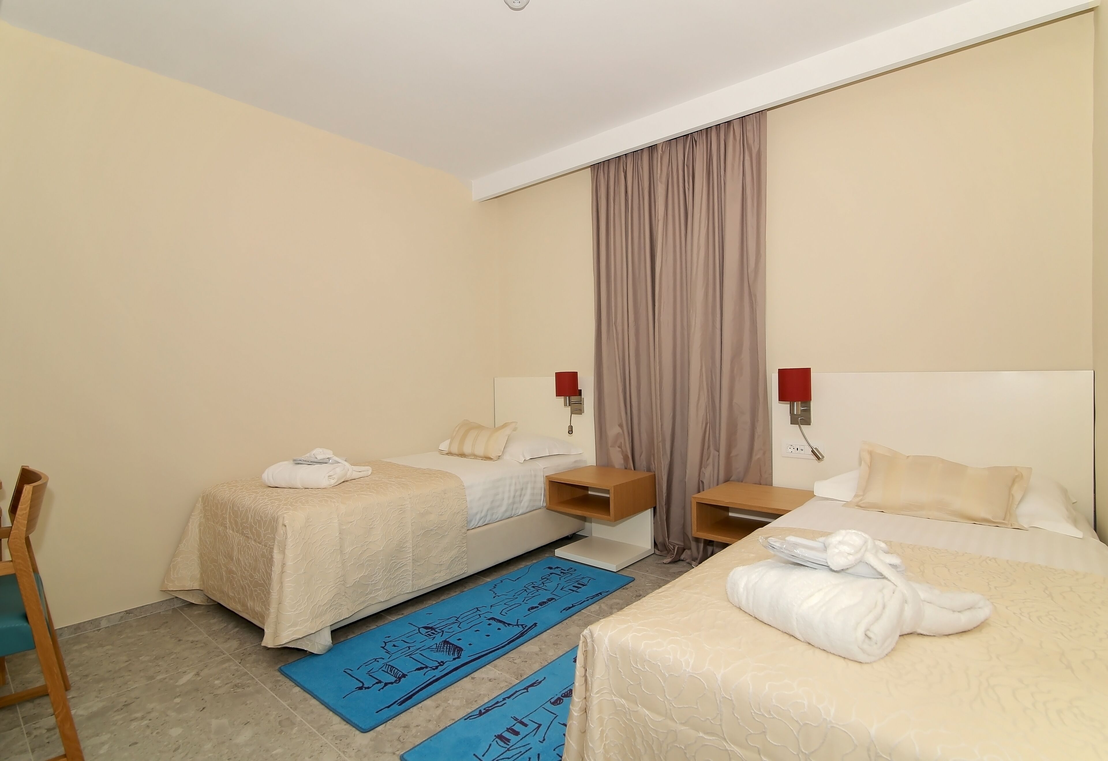 A hotel room with two beds, a desk, and a chair.