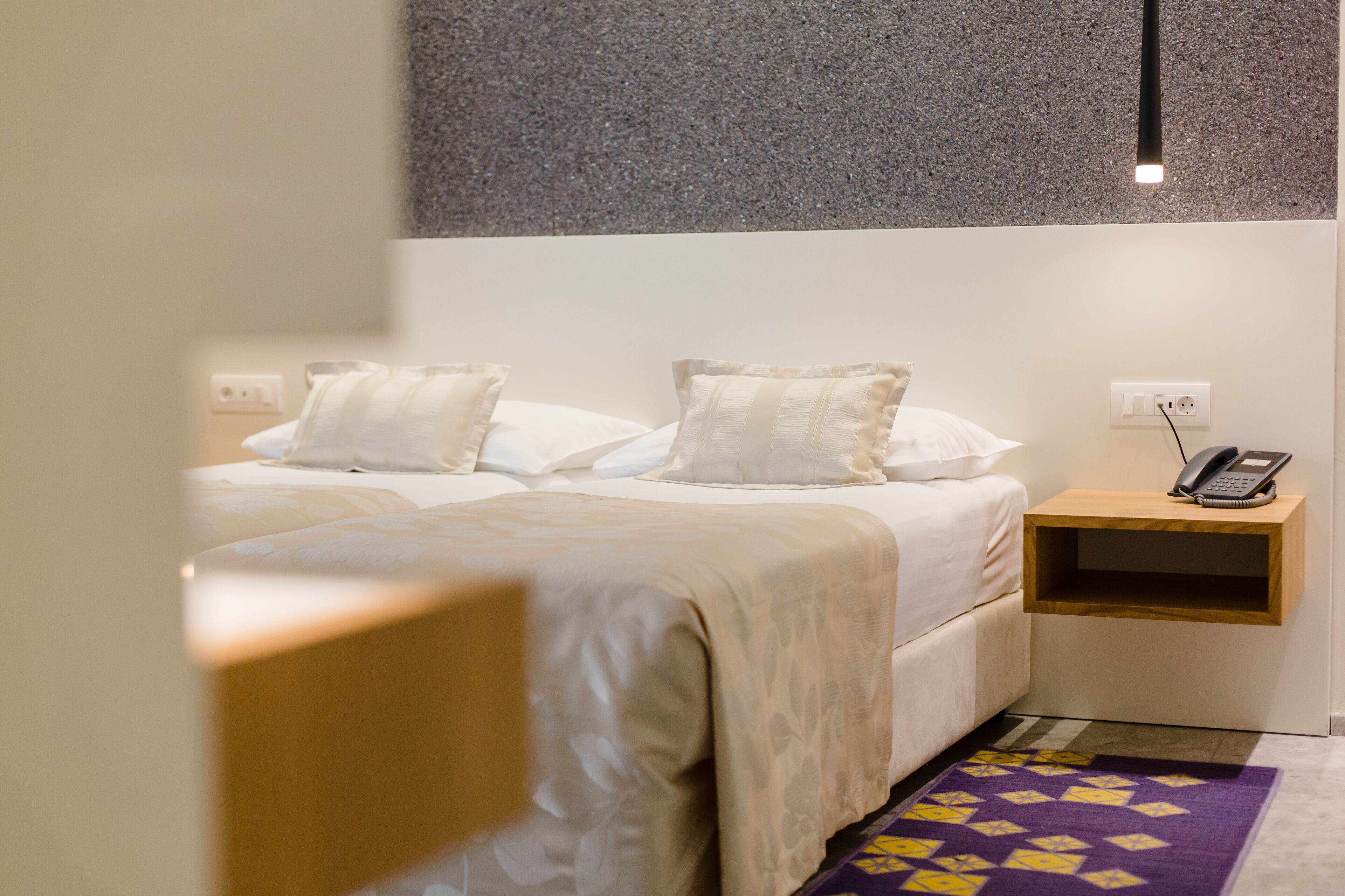 Una habitación de hotel con una cama, una mesita de noche y un teléfono.