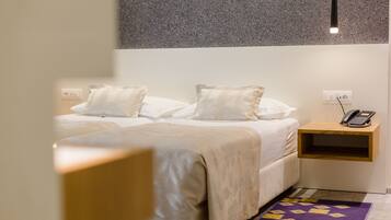 A hotel room with a bed, bedside table, and a phone.