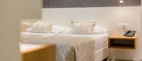 A hotel room with a bed, bedside table, and a phone.