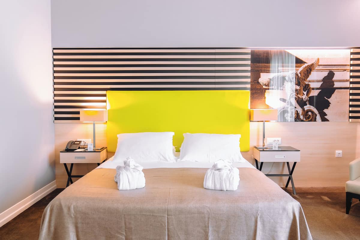 Ein Hotelzimmer mit einem großen Bett, zwei Nachttischen, einer Lampe und einem Bild an der Wand.