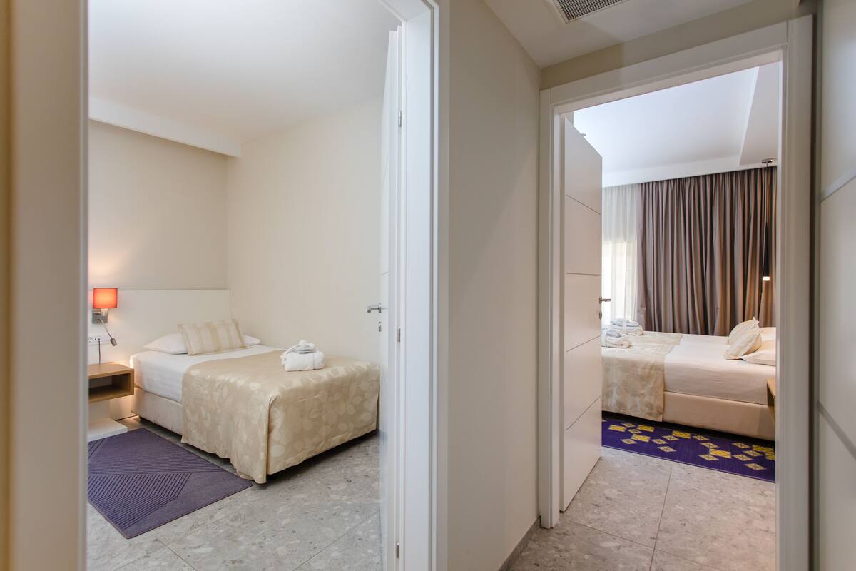 Ein Hotelzimmer mit zwei Betten, einem Nachttisch, einer Lampe und einem durchgegangenen Tür erkennbaren Badezimmer.