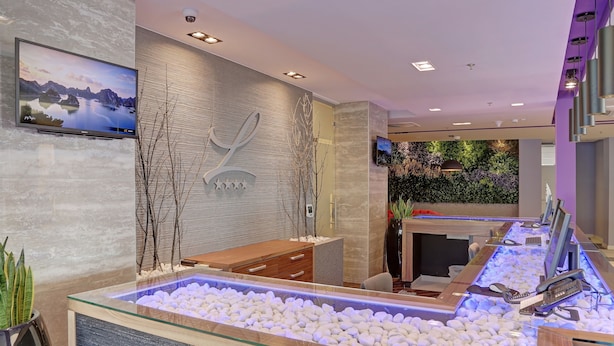 A modern reception area with a large aquarium, wooden reception desk, and a mounted television. - Hotel Lero (Dubrovnik)