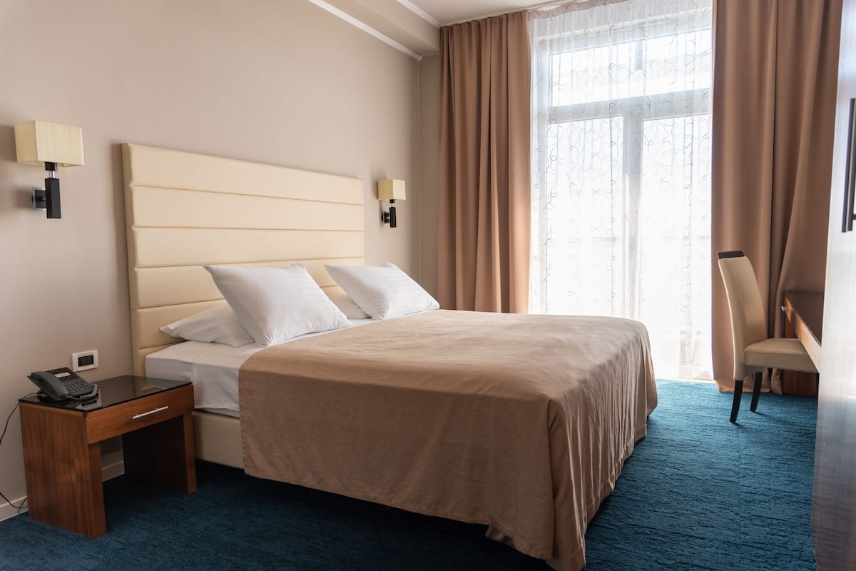 Ein Hotelzimmer mit einem großen Bett, Nachttischen, einem Schreibtisch und einem Sessel.