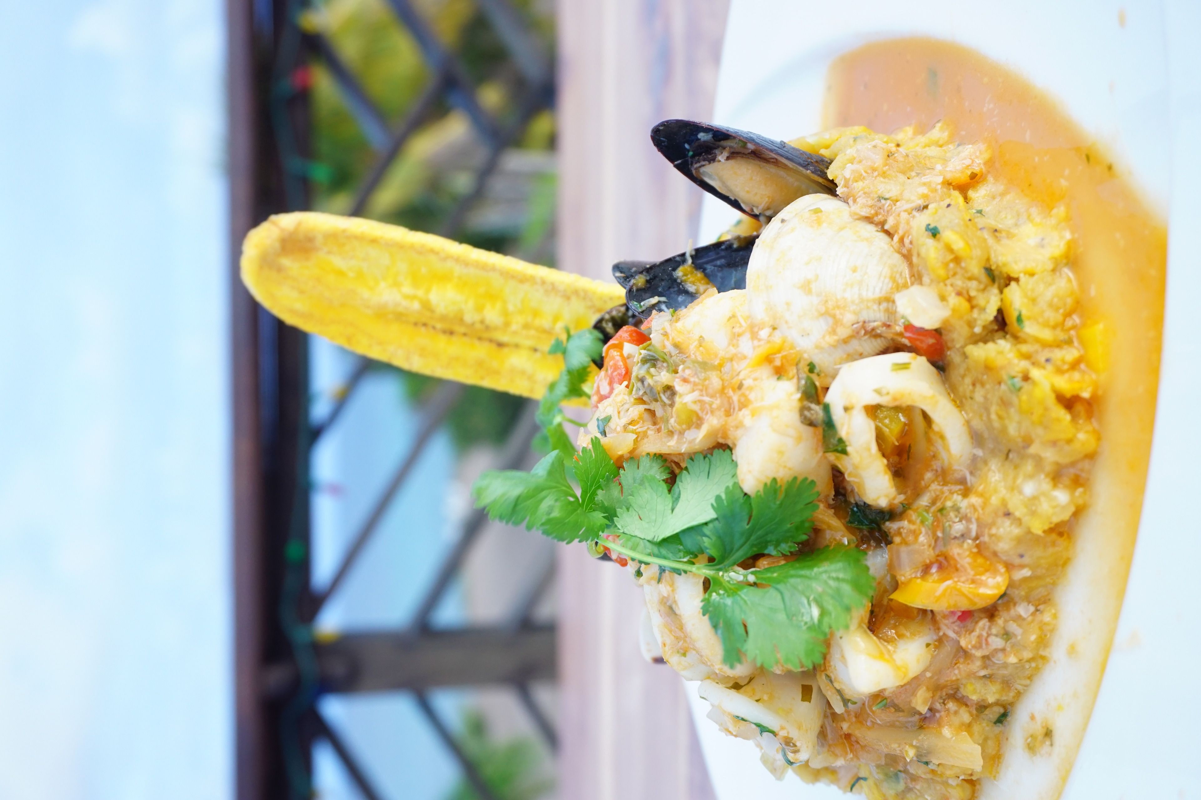 Un plat de fruits de mer composé de moules, de crevettes et de maïs, servi dans une assiette blanche.