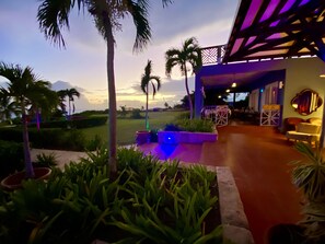 Eine Terrasse mit Palmen, ein Pool mit blauer Beleuchtung und eine Sitzgelegenheit mit Tischen und Stühlen.