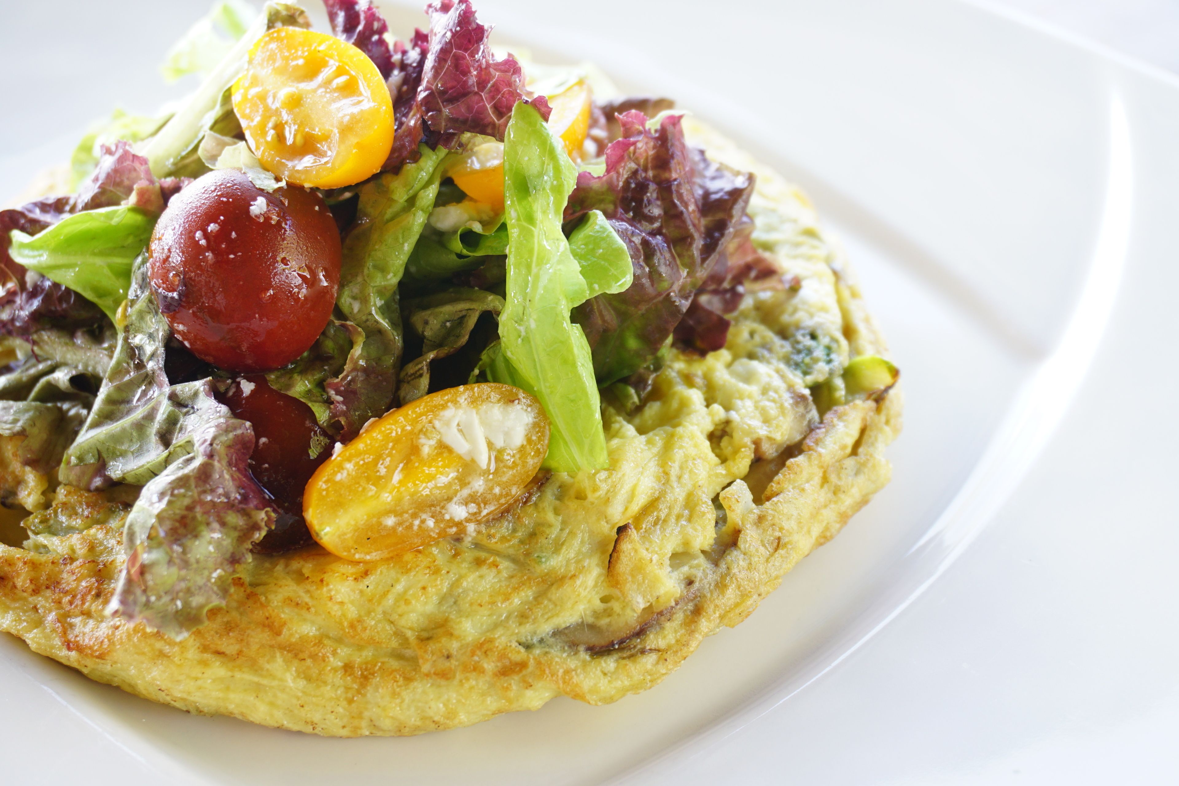 A plate with a salad and a slice of omelette.