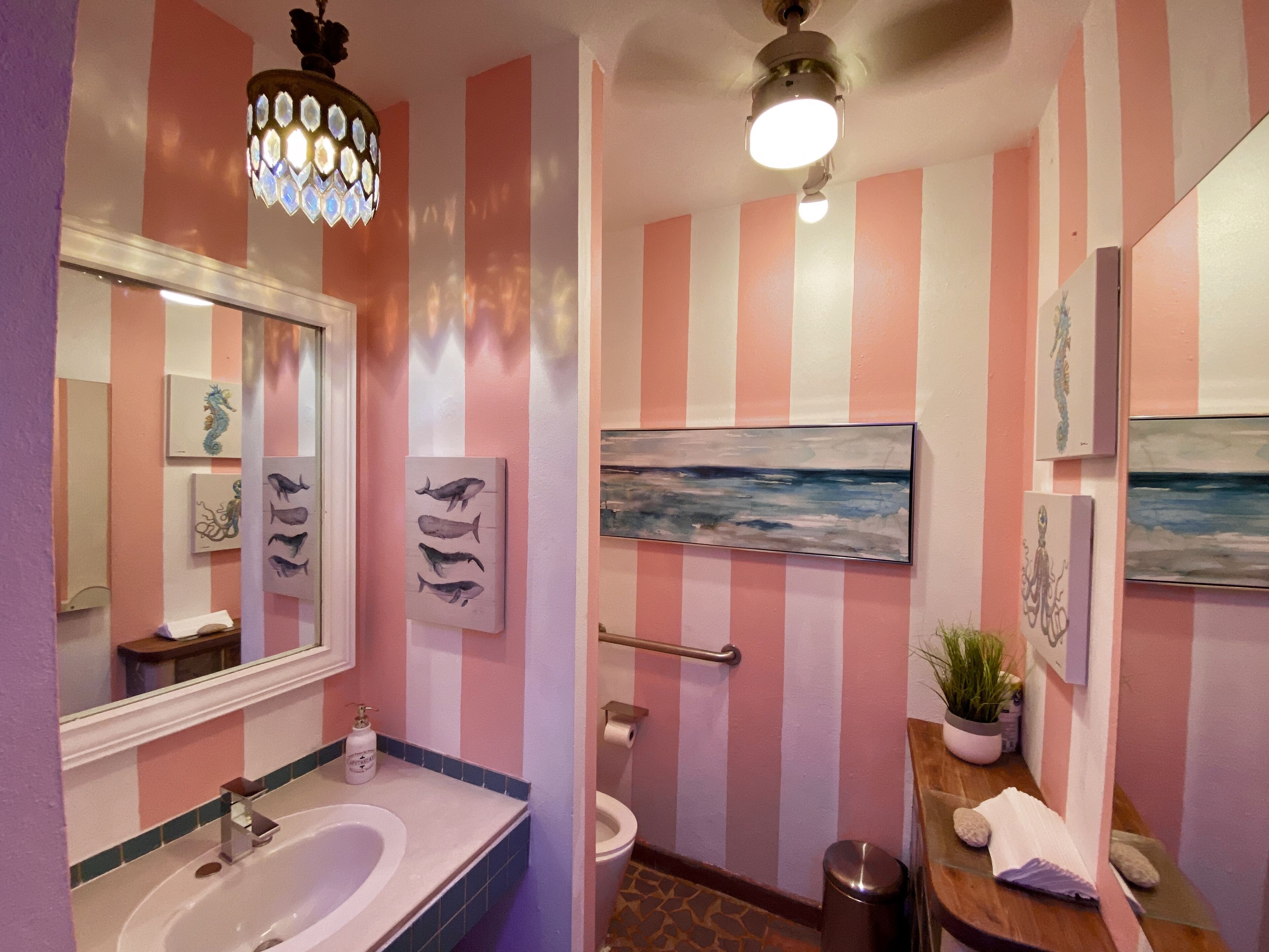 Een badkamer met een grote spiegel, een wastafel, een toilet en een douche.