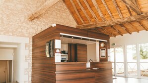 A reception desk with a wooden finish, a clock, and a sign indicating WiFi availability. - Terres de France - Appart'Hôtel La Roche Posay (La Roche-Posay)
