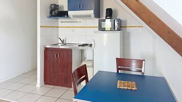 A compact kitchen with a dining table, chairs, and a coffee maker.