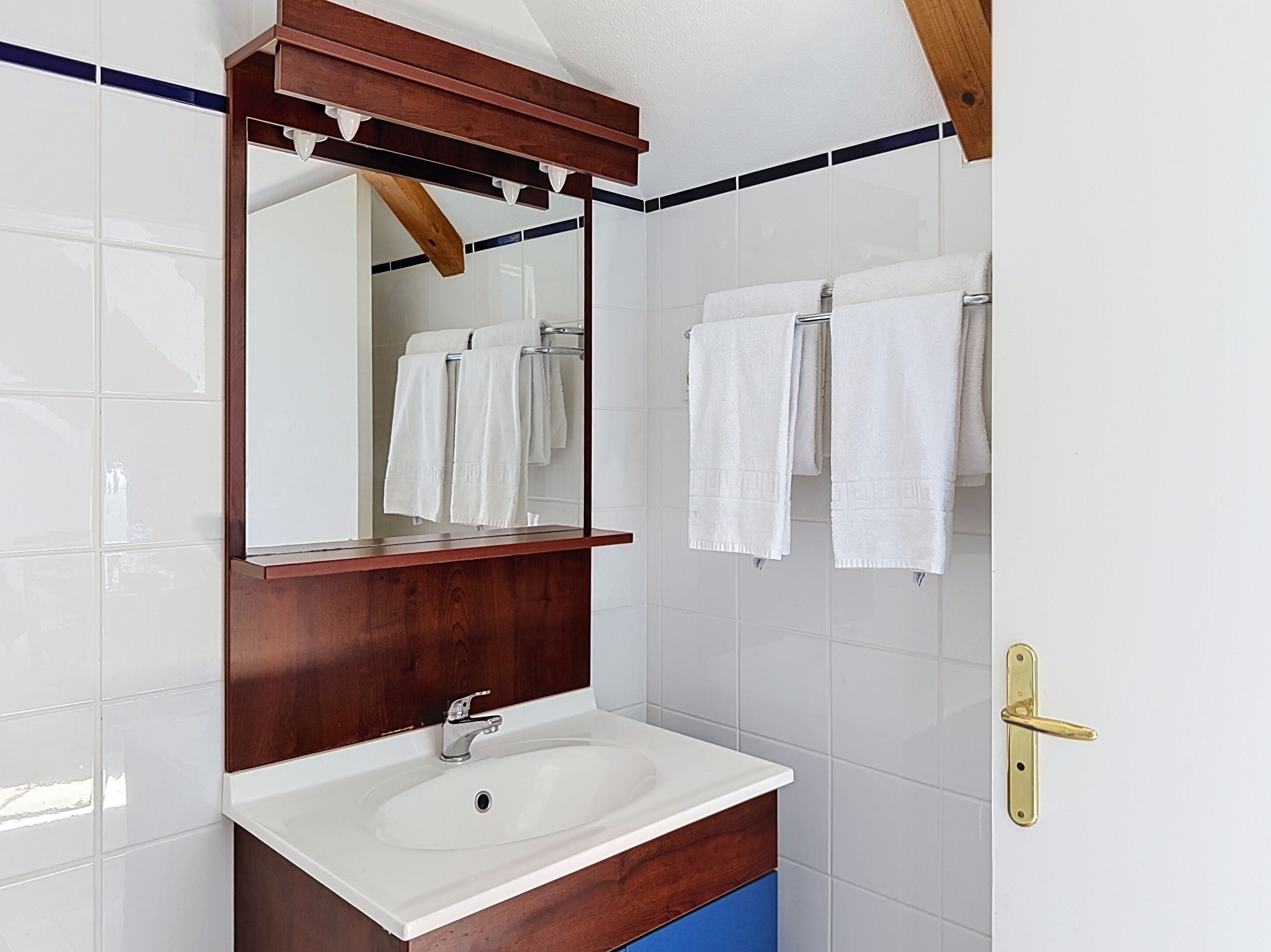 A bathroom with a wooden vanity, a white sink, and a mirror.