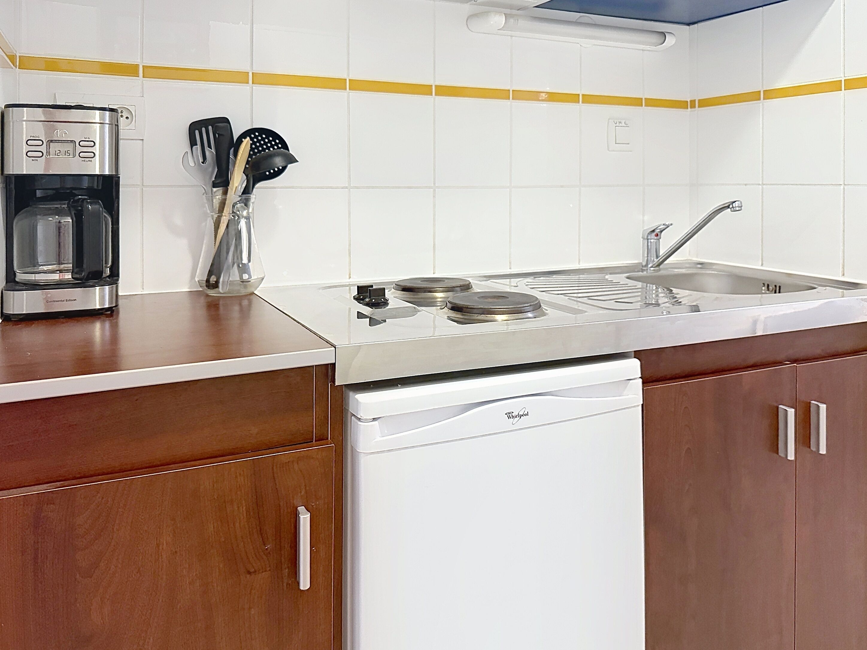 Una cocina con cafetera, lavabo y lavavajillas.