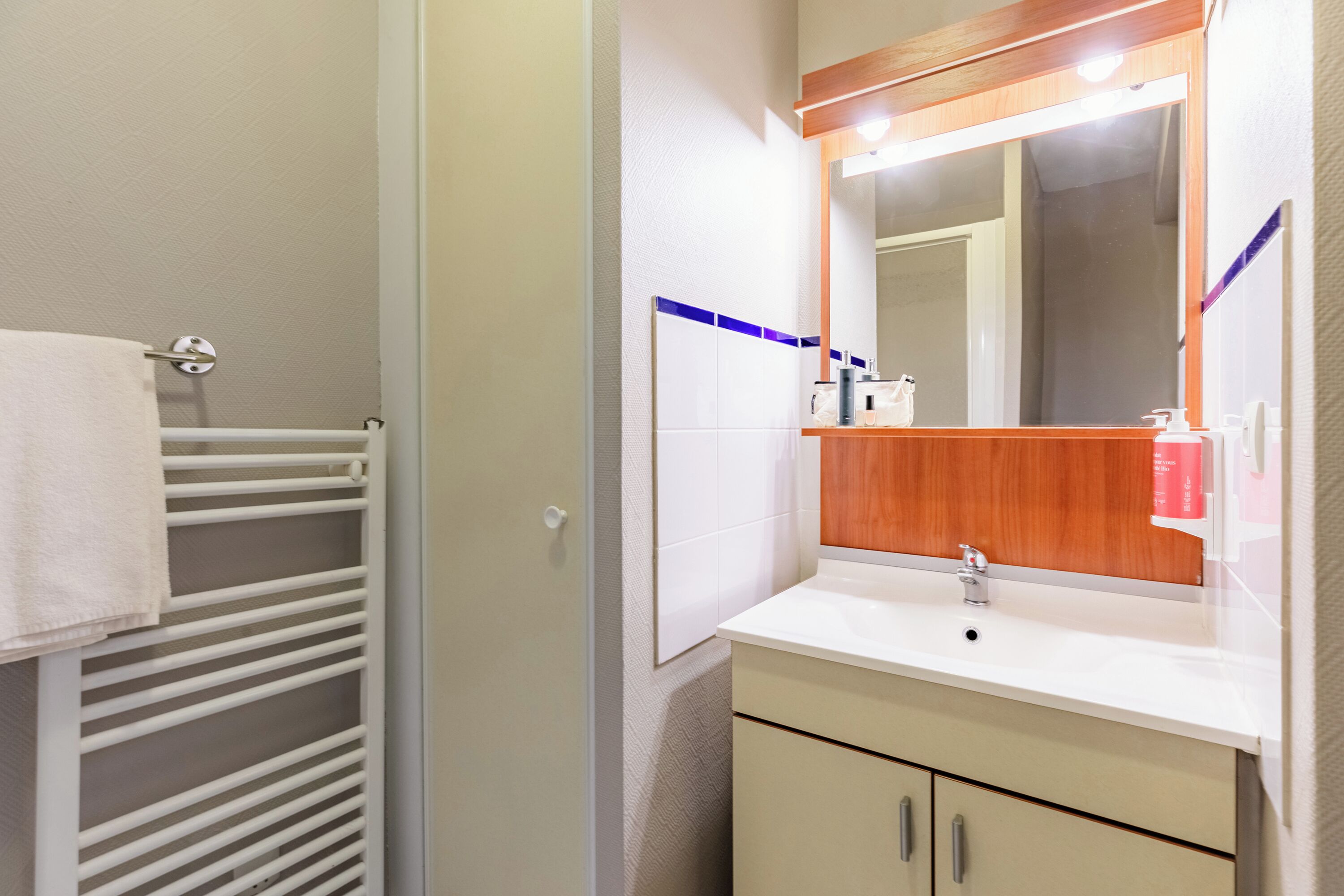 A bathroom with a white sink, mirror, and towel rack.