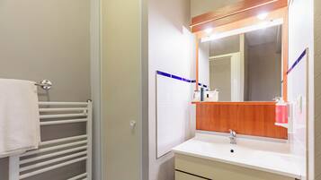 A bathroom with a white sink, mirror, and towel rack.