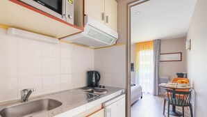 A modern kitchen with a microwave, kettle, and sink. There is a dining area with a table and chairs. - Appart'City Confort Nantes Cité des Congrès (Nantes)