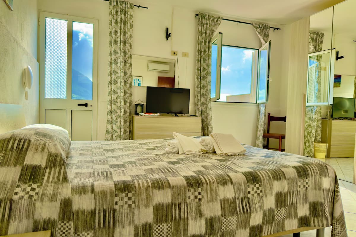 Ein Hotelzimmer mit Bett, Fernseher, Kommode und einem Fenster mit Vorhängen.