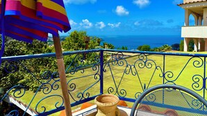 A balcony with a view of the ocean, a decorative umbrella, and a metal railing. - Hotel Villa Fiorentina (Casamicciola Terme)