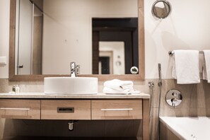 Un baño con lavamanos blanco, espejo y ducha.