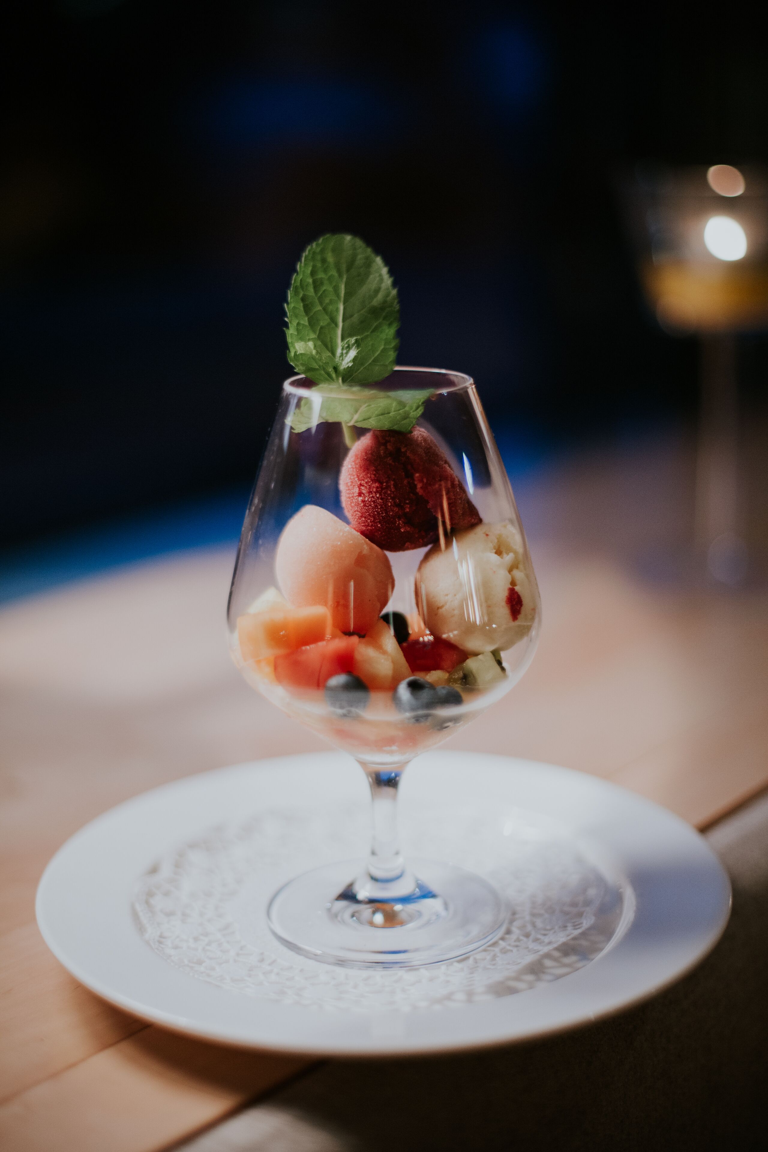 A dessert glass with various fruits on a white plate.