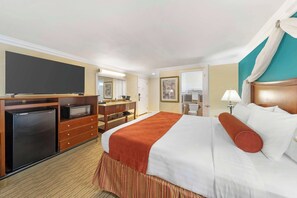 A hotel room with a bed, a television, a desk with a computer, and a bathroom.