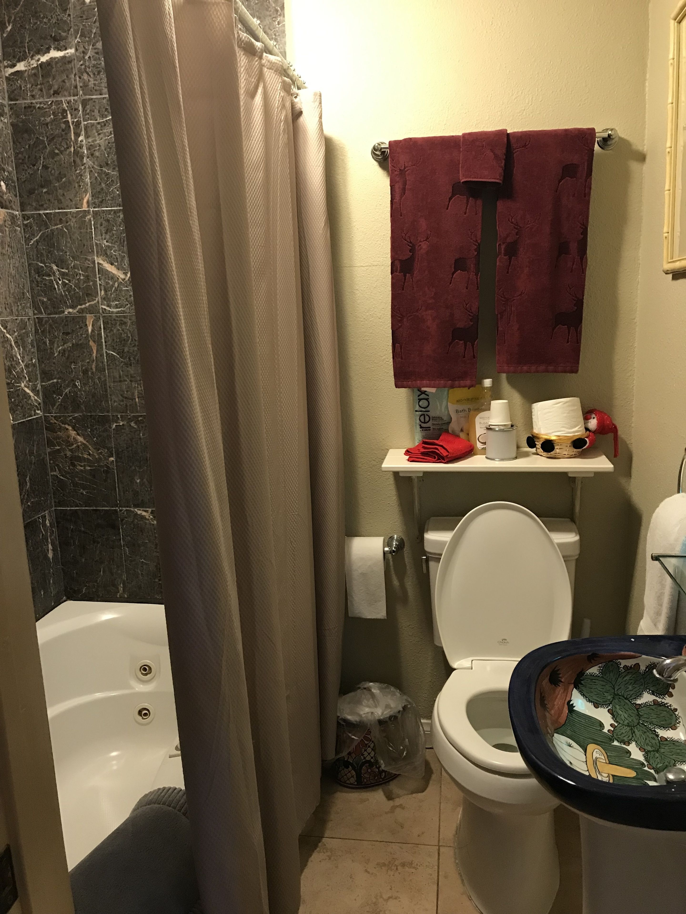 A bathroom with a bathtub, toilet, and sink. There are towels hanging on a rack and a shower curtain partially drawn.