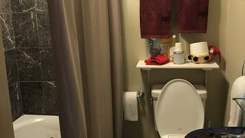 A bathroom with a bathtub, toilet, and sink. There are towels hanging on a rack and a shower curtain partially drawn.