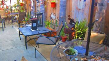 An outdoor patio with metal tables and chairs, potted plants, and a decorative metal sculpture.