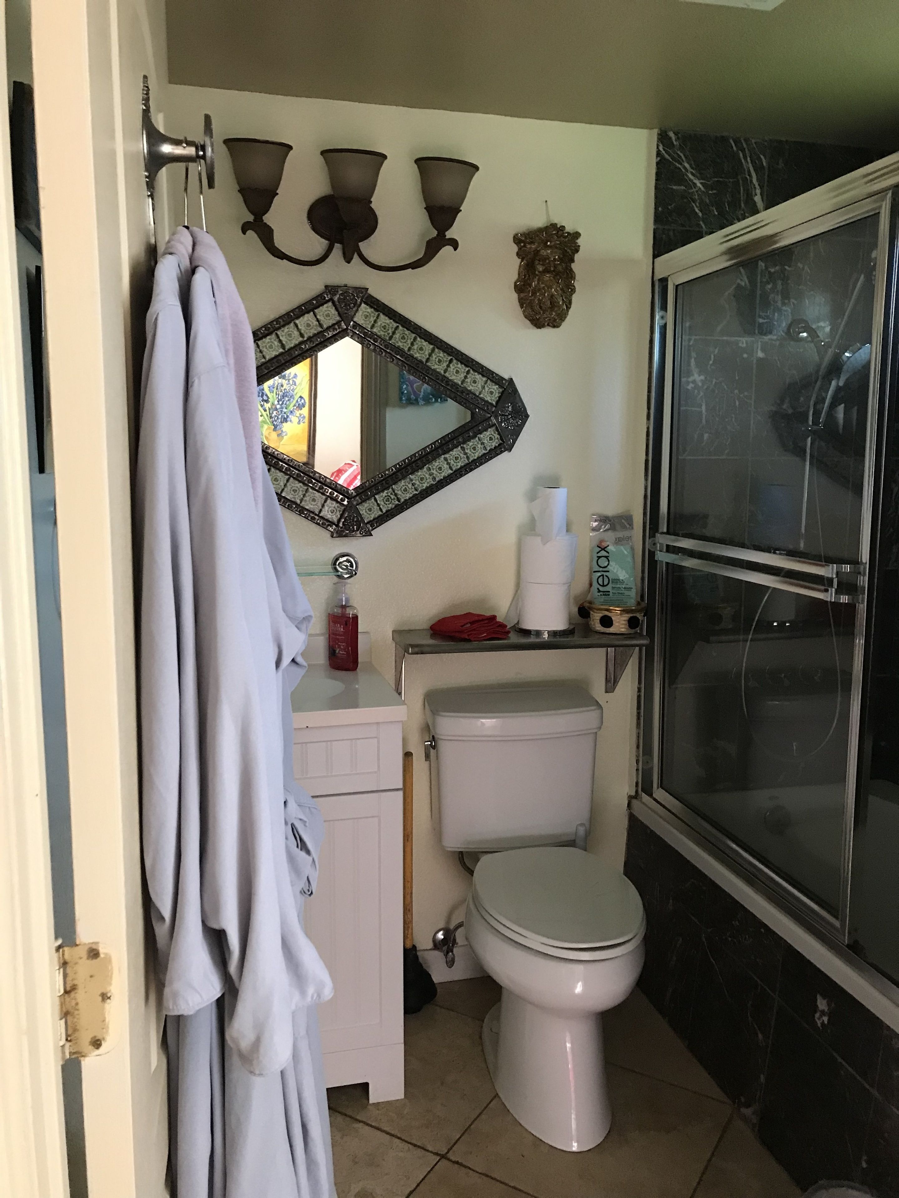 A bathroom with a toilet, a sink, a mirror, and a shower.