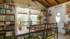 Une salle de lecture accueillante, avec une table en bois, des chaises et des étagères remplies de livres.