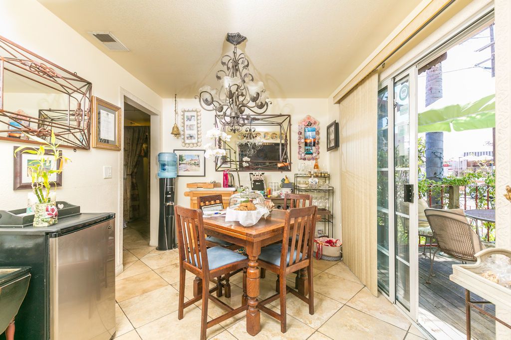 Un espace repas avec une table et des chaises en bois, un lustre et une vue sur une terrasse extérieure, accessible par une porte vitrée.