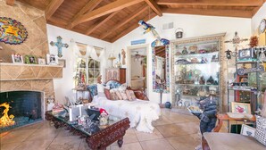 Un salon chaleureux avec une cheminée, un lit et une vitrine remplie d’objets décoratifs.