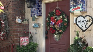 Une entrée avec une porte rouge, une couronne de Noël et une enseigne en forme de cœur pour l’hôtel Always Inn SC.