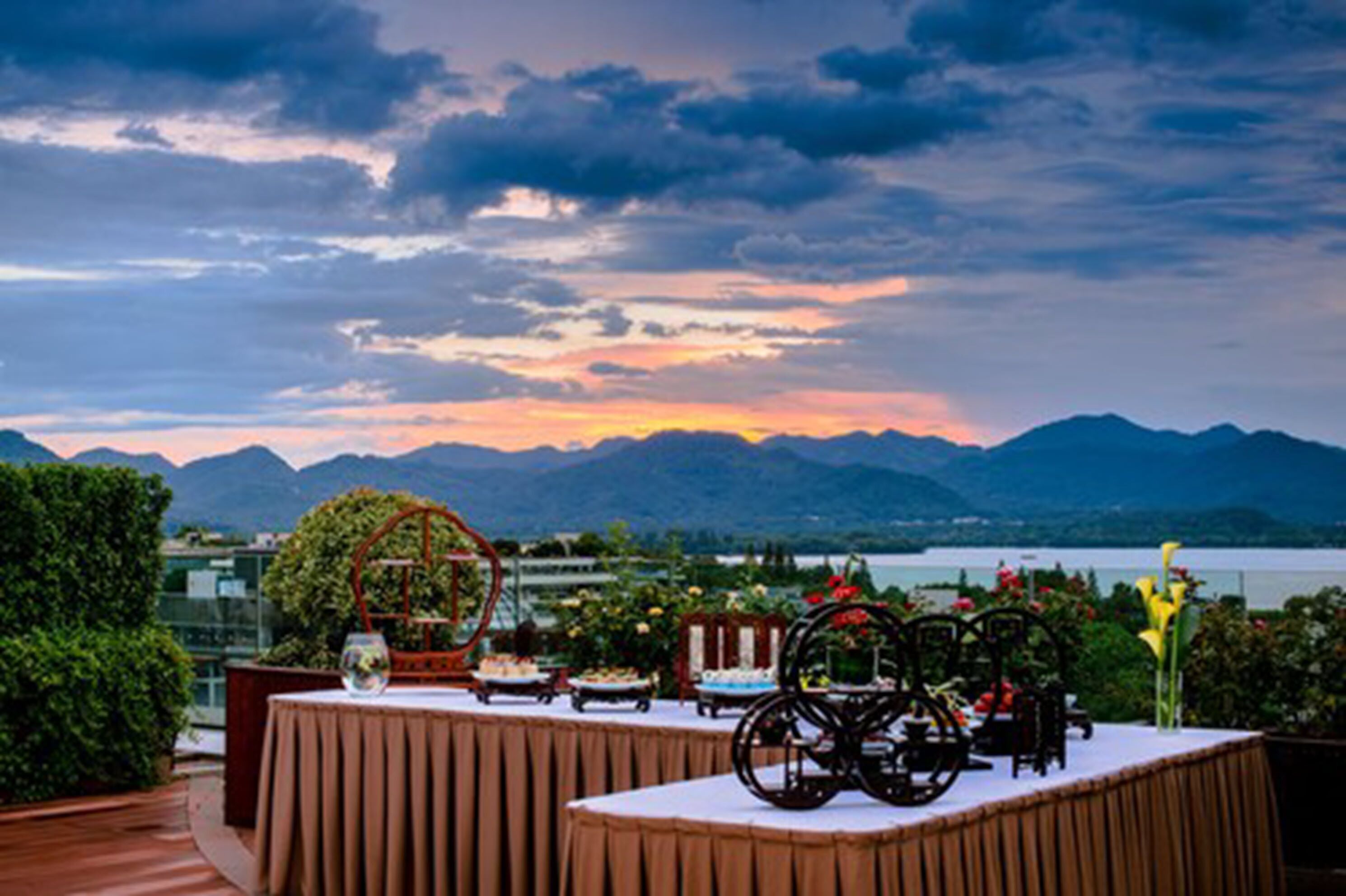 A table set outdoors with a view of mountains and a lake at sunset.