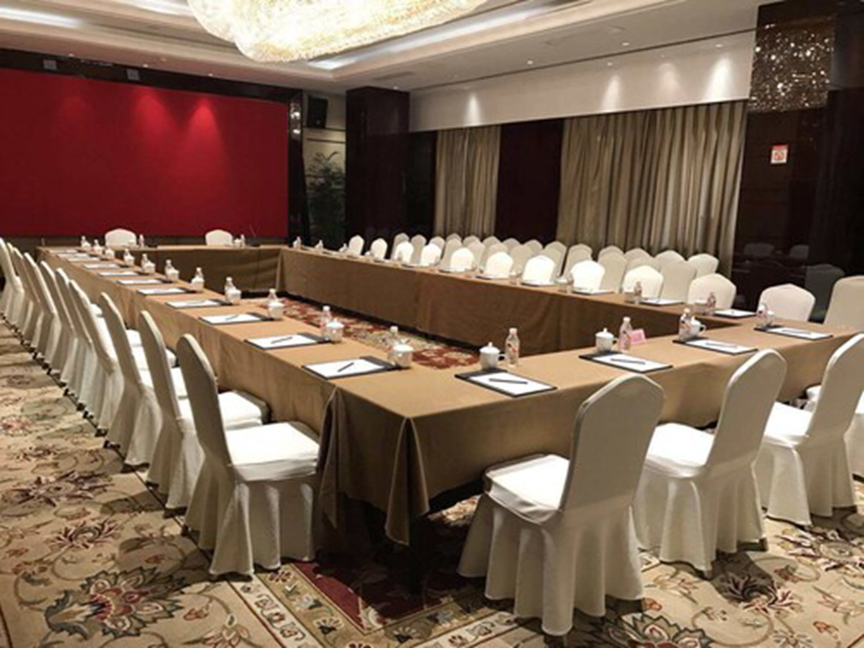 A conference room with a long table, white chairs, and a carpeted floor.