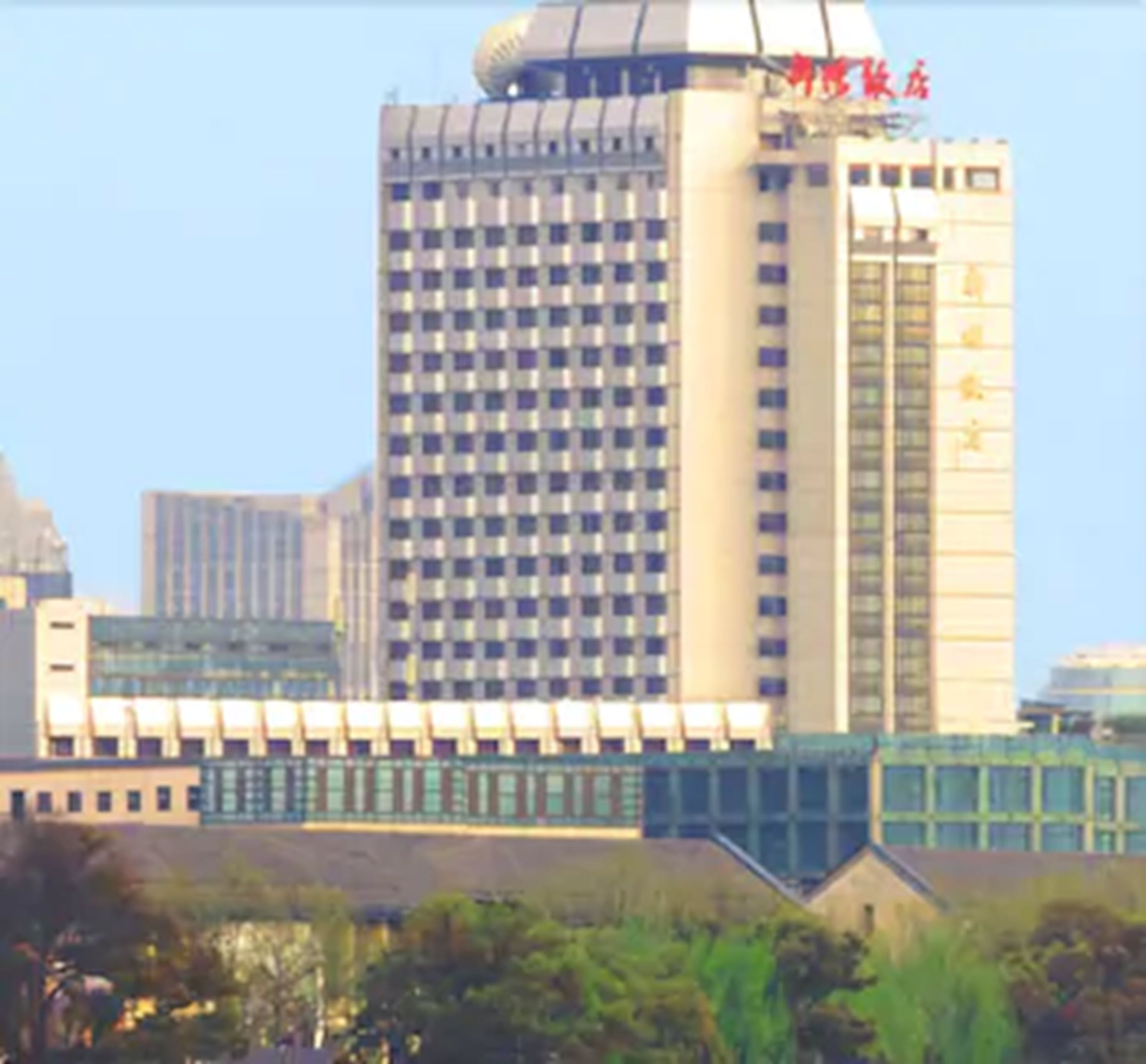 A high-rise building with a grid-like facade and a prominent dome structure on top.